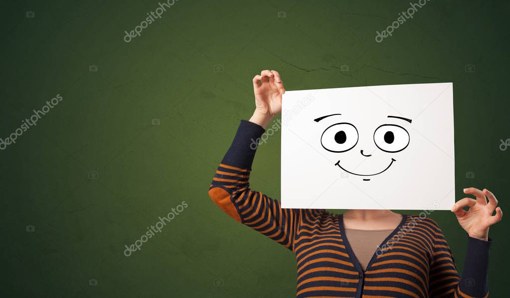 Student holding a paper with laughing emoticon in front of his face