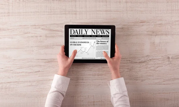 Hand with tablet reading news