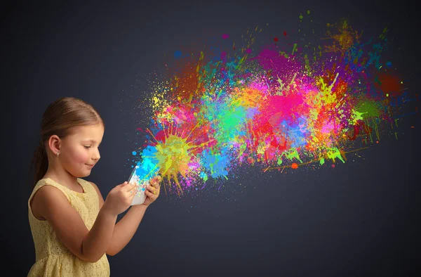 Menina segurando comprimido com respingo colorido ao redor — Fotografia de Stock