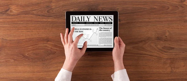 Hand with tablet reading news