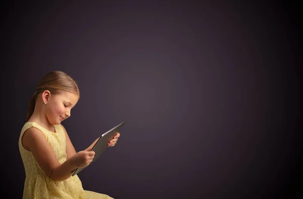 Roztomilá holčička použití tabletu s tmavým pozadím — Stock fotografie