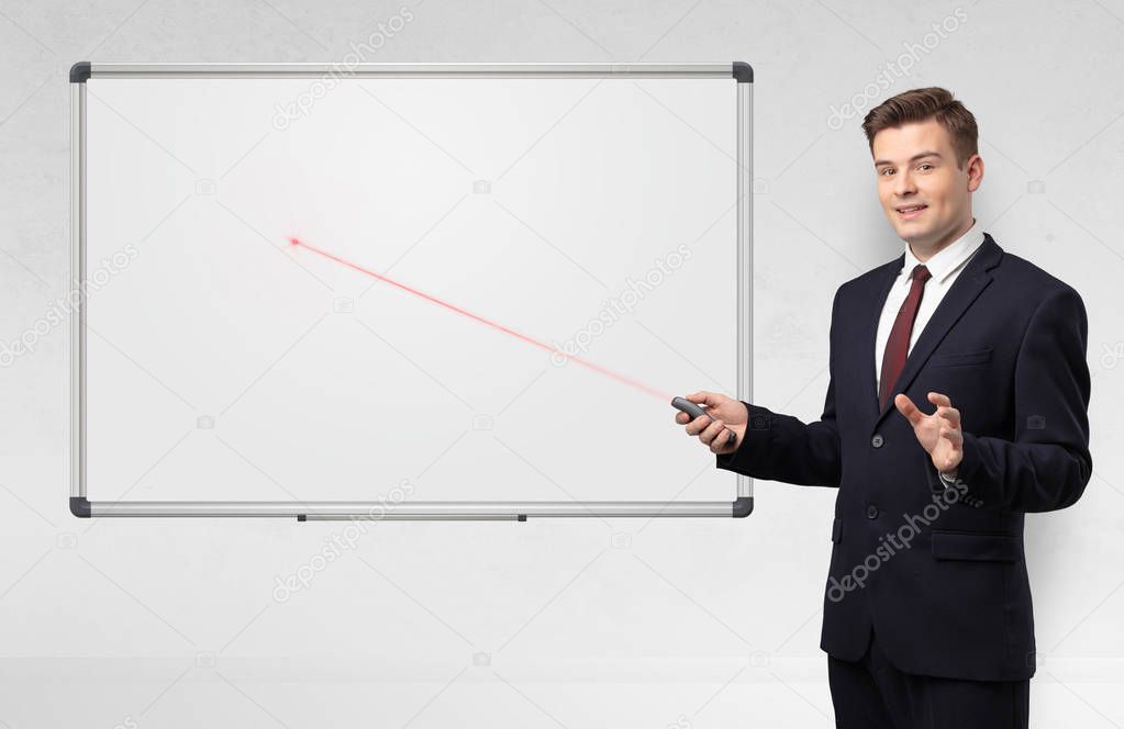 Businessman with laser pointer and copyspace white blackboard