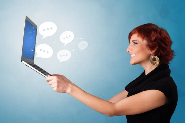 Kvinna som håller laptop med pratbubblor — Stockfoto