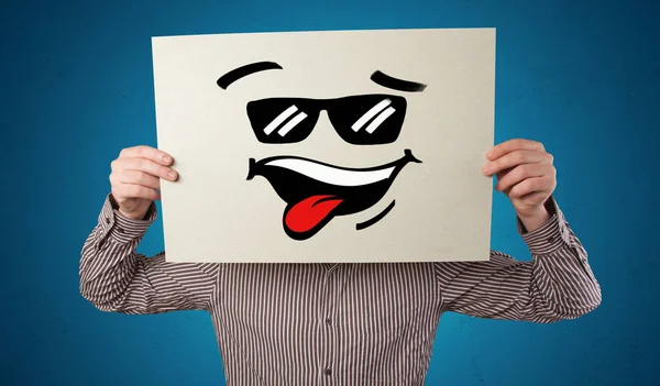 Persona sosteniendo un papel con cara de emoticono fresco —  Fotos de Stock