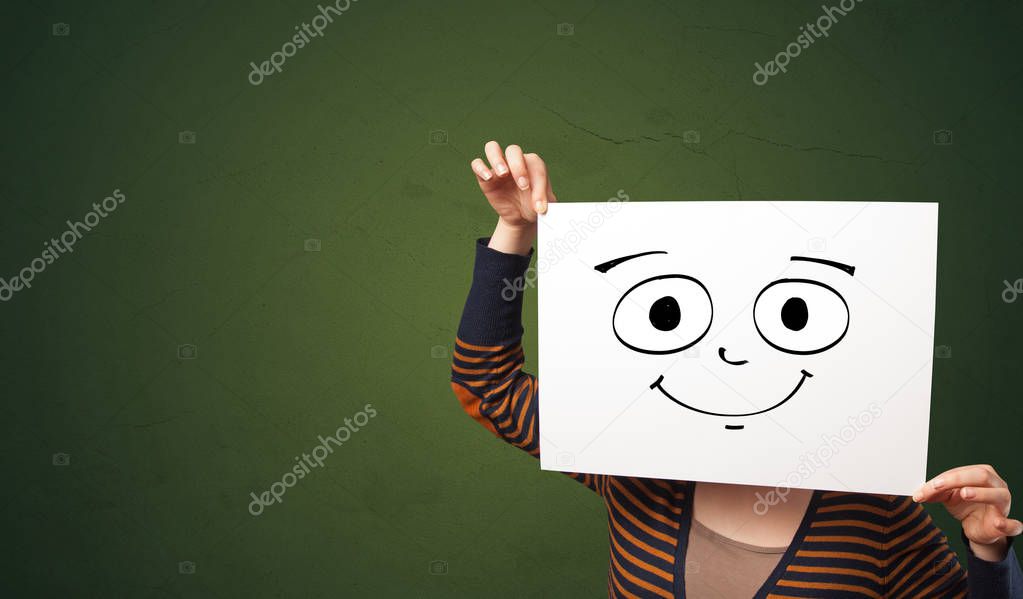 Student holding a paper with laughing emoticon in front of his face