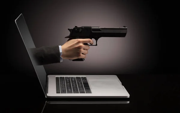 Рука з пістолетом, що виходить з ноутбука — стокове фото