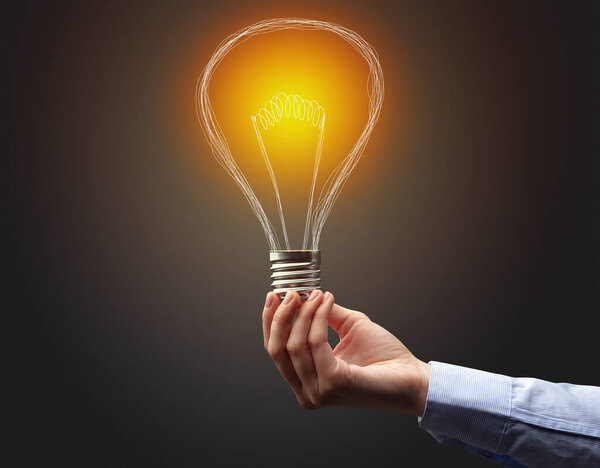 рука держа лампочку на темном фоне