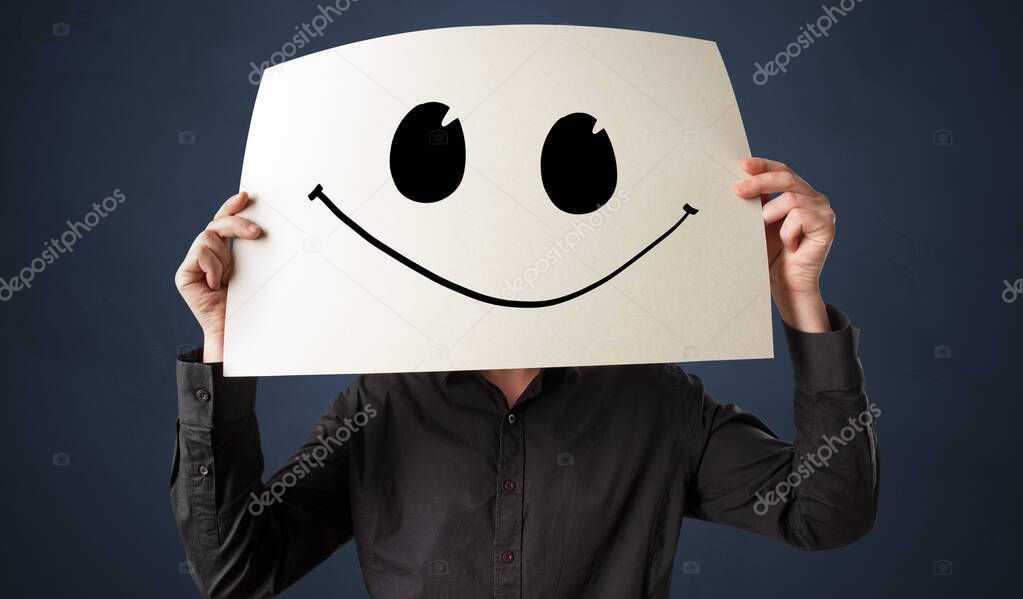 Person holding a paper with funny emoticon in front of her face