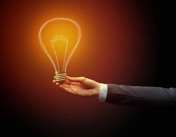 Hand holding light bulb on dark background — Stock Photo, Image