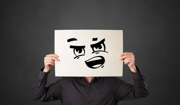 Pessoa segurando um papel com emoticon engraçado na frente de seu rosto — Fotografia de Stock