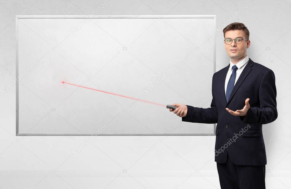 Businessman with laser pointer and copyspace white blackboard