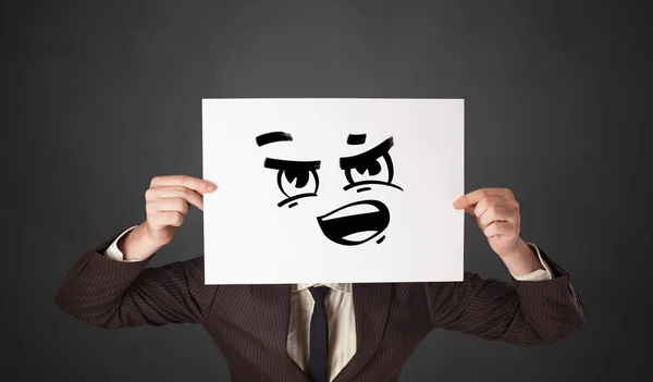 Pessoa segurando um papel com emoticon engraçado na frente de seu rosto — Fotografia de Stock