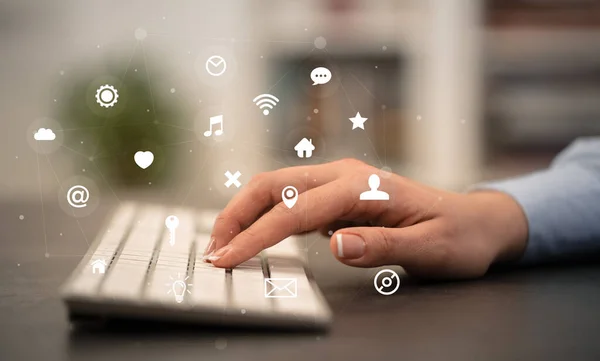 Hand typing on keyboard with application icons around — Stock Photo, Image