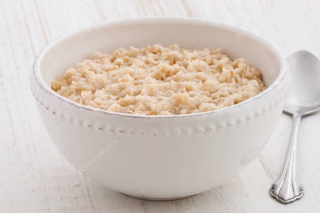 Delicious nutritious and healthy fresh old fashioned oatmeal on antique wood table