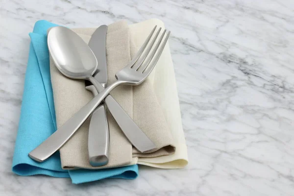 silverware and hemstitch napkin on antique carrara marble