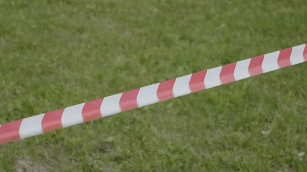 Red and white temporary perimeter tape on the background of green grass — Stock Photo, Image