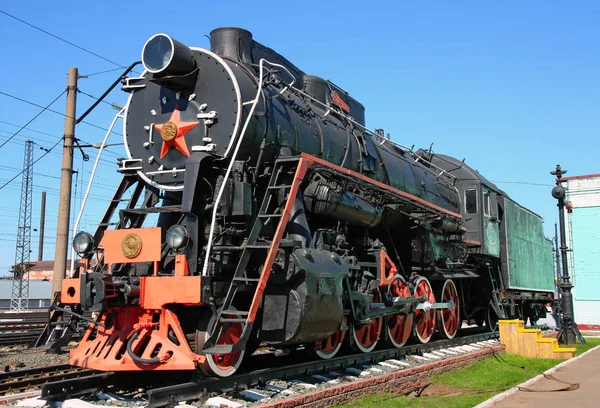 Oude zwarte locomotief in het spoorwegdepot op de parkeerplaats — Stockfoto