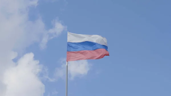 Rosyjska Flaga na maszcie machając w wiatr przeciwko błękitne niebo z chmur — Zdjęcie stockowe