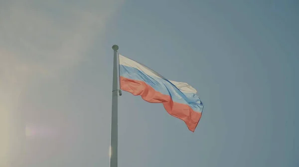 Rosyjska Flaga na maszcie machając w wiatr przeciwko błękitne niebo z chmur. — Zdjęcie stockowe