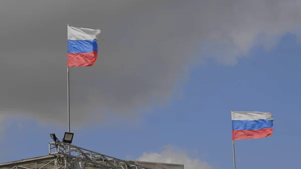 Russian flag on the flagpole waving in the wind against a blue sky with clouds — Stock Photo, Image