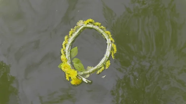 Wreath of dandelion flowers floats on water. — Stock Photo, Image