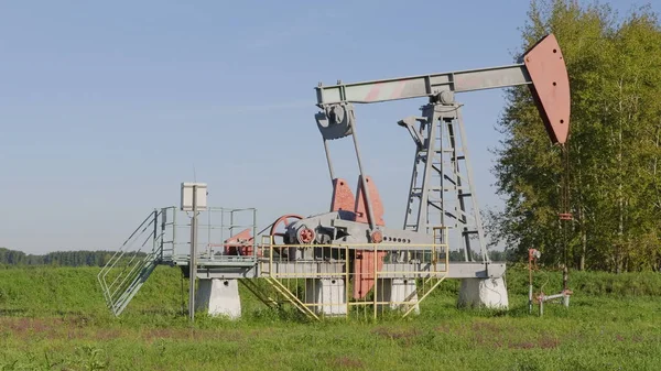 Operating oil and gas well in oil field, profiled against the blue sky — Stock Photo, Image