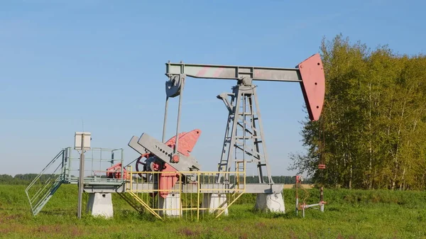 Operando poço de petróleo e gás no campo de petróleo, perfilado contra o céu azul — Fotografia de Stock