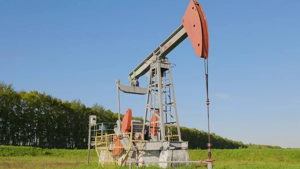 Pozo de petróleo y gas operativo en el campo petrolífero, perfilado contra el cielo azul — Foto de Stock