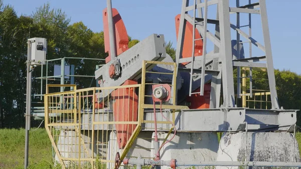 Exploitation d'un puits de pétrole et de gaz dans un champ pétrolifère, profilé contre le ciel bleu — Photo