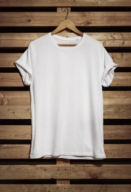 Kopya alanı ile ahşap arka plan asılı boş beyaz t-shirt 