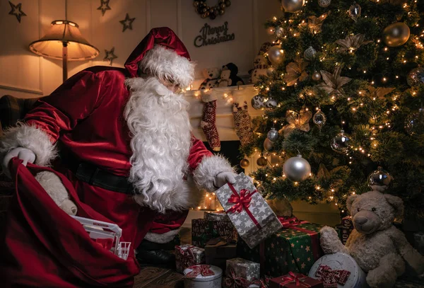 サンタ クロースがクリスマス ツリーの下にプレゼントを置く — ストック写真