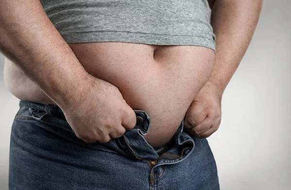 Close up van overgewicht man probeert te dragen kleine jeans — Stockfoto