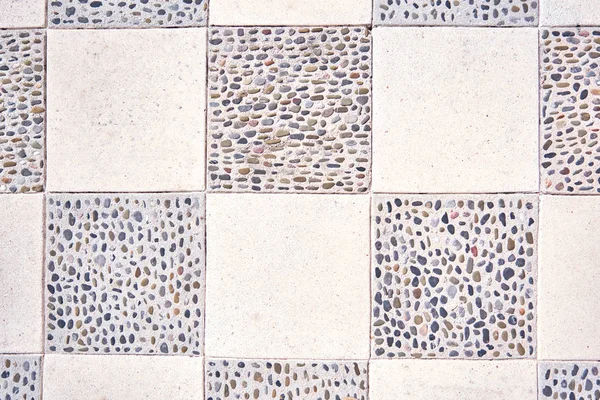 The texture of stone tiles with sea pebbles in cement closeup.
