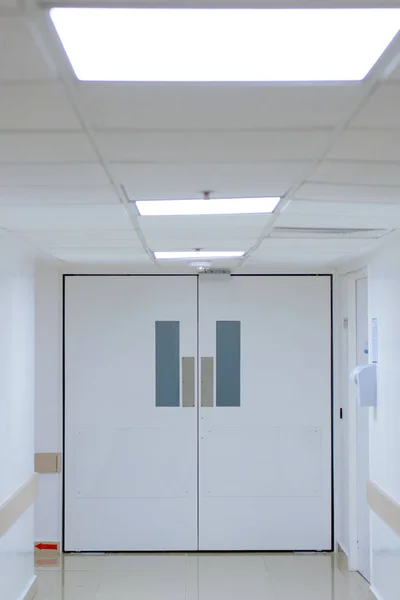 A huge white door in the white corridor in the hospital.