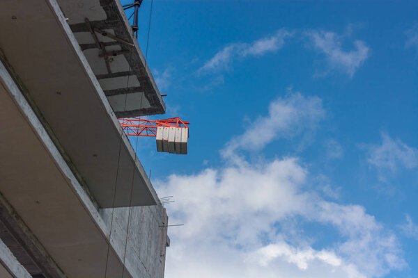 Building against the sky. Crane and building construction site against blue sky.