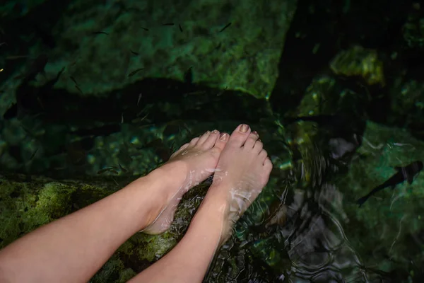 Women's feet in the water with fish. — Stock Photo, Image