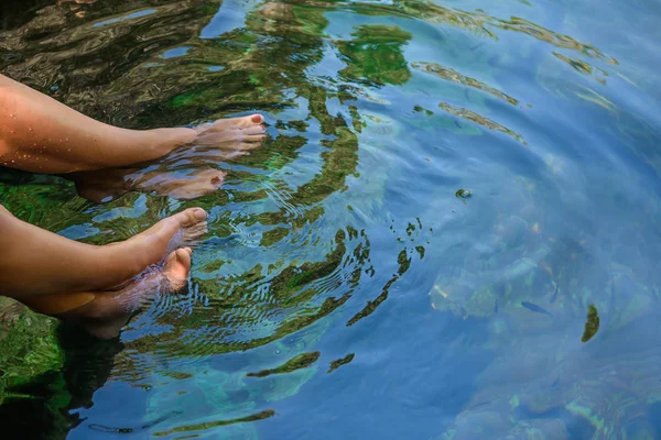 Womens feet in the water with fish.