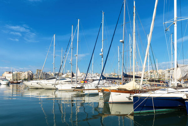 Yachts docked in sea port in Piraeus, Athens, Greece. Modern sailboats parked in beautiful marina. Panoramic scenic view of sail yachts in blue water. Concept of luxury marine relax and vacation.
