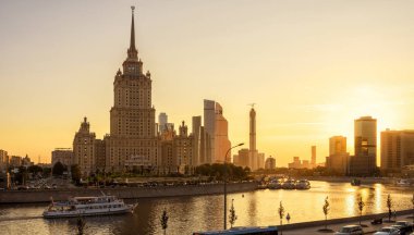 Moskova - 27 Ağustos 2018: Gün batımında Otel Ukrayna (Radisson Royal) ile Moskova'nın güzel panoramik manzarası, Rusya. Yaz akşamı Moskva Nehri'nin güneşli panoraması. Moskova Cityscape ve güneş ışığında turist gemileri.