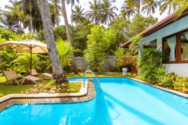 Sri Lanka - 4 Kasım 2017: Havuz şemsiye ve plaj yatak lüks tropikal Otel'in bahçesinde. Avluda mavi temiz su ile güzel Yüzme Havuzu. Güneşli pastoral bahçesinde bir relax.