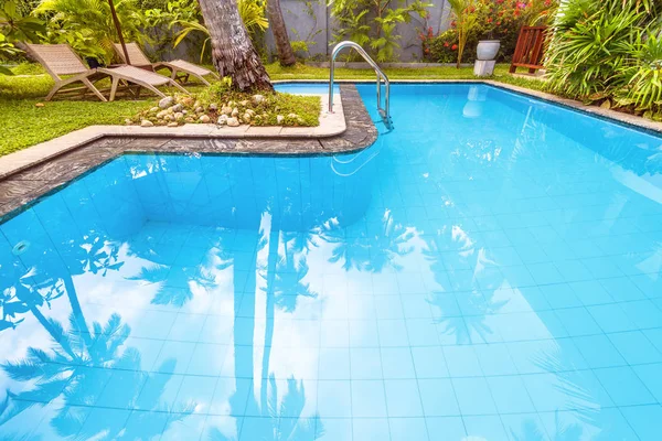 Konut ev ya da tropikal Otel havuzunda. Güzel yüzme havuzu yaz aylarında avluda. Arka bahçesinde rahatlatıcı için sakin bir yer. Havuzu arka plan için güzel bir bahçe içinde mavi temiz su ile.