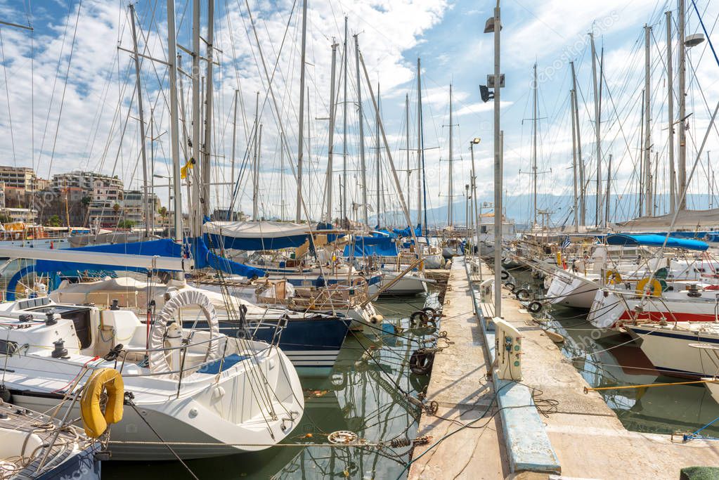 Yachts docked in sea port in Piraeus, Athens, Greece. Modern sailing boats mooring in beautiful marina in summer. Scenic view of nice yachts in harbor. Concept of luxury marine relax and vacation.