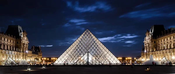 Paris - 25 Eylül 2013: Louvre Musée du Louvre de Paris geceleri. Ünlü Louvre Fransa en iyi turistik yerlerinden biridir. Panoramik Louvre ve Cam Piramit akşamları. Alacakaranlıkta ışıklı Louvre.