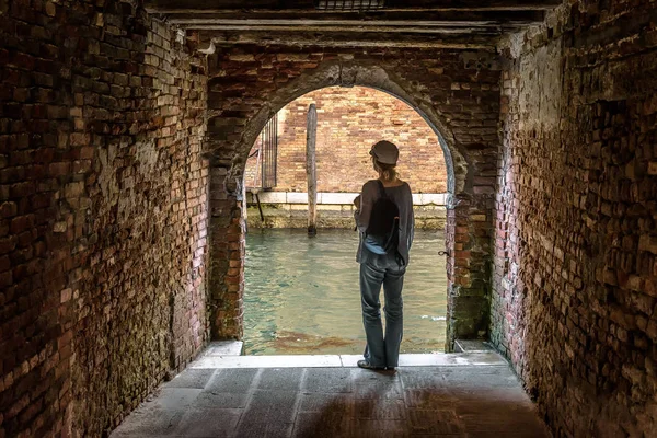 Woman stands at exit to canal from courtyard, Veneza, Itália — Fotografia de Stock