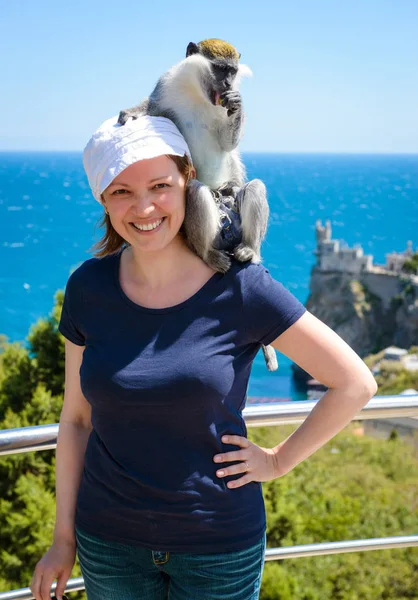 Joven mujer sonriente posando con un mono en la costa del Mar Negro de Crimea — Foto de Stock