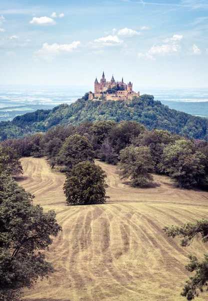 Hohenzollern Castle or Burg atop mount in summer, Germany. Famous old Gothic castle is landmark in Baden-Wurttemberg. Scenic view of fairytale German castle like palace in Swabia countryside.