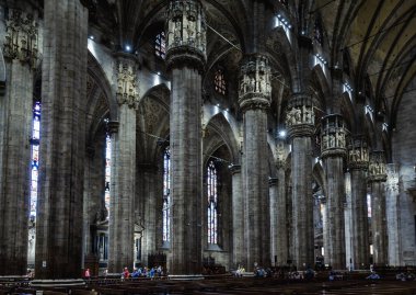 Milan, İtalya - 16 Mayıs 2017: Milano Katedrali veya Duomo di Milano 'daki insanlar. Büyük bir Katolik kilisesi, Milano 'nun en önemli simgesidir. Büyük koyu Gotik katedralin içi, büyük sütunların perspektifi.
