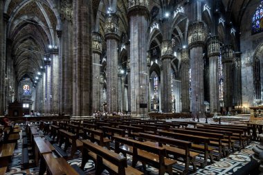 Milan, İtalya - 16 Mayıs 2017: Büyük Milan Katedrali veya Duomo di Milano 'nun içi. Büyük bir Katolik kilisesi, Milano 'nun en önemli simgesidir. Karanlık Gotik katedralinin içinde, sıralardan ve büyük sütunlardan oluşan bir panorama.