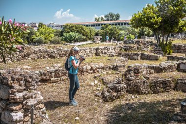 Yunanistan 'ın Atina kentinde Antik Agora' yı ziyaret eden bir kadın görülüyor. Atina 'nın turistik merkezi. Genç ve güzel bir kadın Atina şehir merkezinde klasik Yunan harabelerinin fotoğraflarını çekiyor. Seyahat ve tatil kavramı.