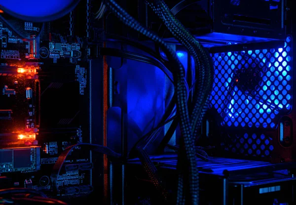 Computer illuminated by internal LED RGB lights, hardware inside open high performance desktop PC. The open tower of gaming computer for wallpaper. Concept of computer repair and modern technology.